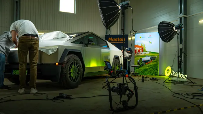 Inspelning i en hall: en folierad Cybertruck, två ljusriggar med softboxar och en gimbal med kamera.